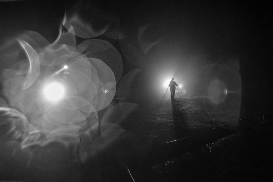 podróżnicy wędrujący w nocy oświetlający sobie drogę czołówkami
