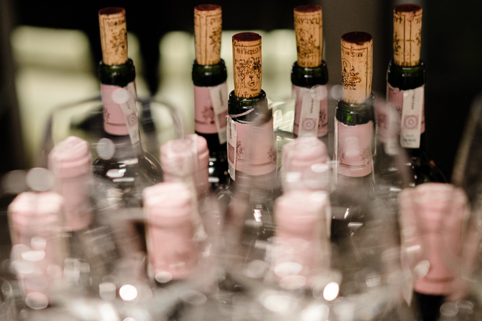 Zdjęcie reportażowe z kolacji w restauracji przedstawiające zakorkowane butelki czerwonego wina